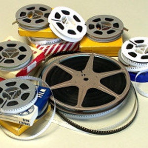 May include: A collection of vintage film reels in various sizes and colors, some are in their original boxes. The reels are made of metal and plastic and have a variety of designs.