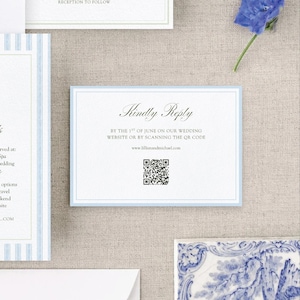 Op de afbeelding: Trouwuitnodigingsset met een lichtblauwe rand en de tekst "Kindly Reply". De uitnodiging bevat een QR-code en websiteadres. Andere kaarten in de set hebben blauwe strepen en tekst. Een blauwe bloem staat op de achtergrond.