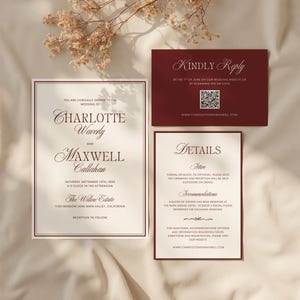 May include: A wedding invitation suite in burgundy and cream. The set includes an invitation with names, date, and venue, a reply card with a QR code, and a details card with attire and accommodation information. The text is in a classic serif font.