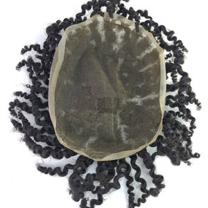 Pu&ograve; includere: Un'extension di capelli ricci marrone scuro con una base in pizzo. I capelli sono acconciati in riccioli stretti e mossi, che si irradiano verso l'esterno dal centro. La base in pizzo &egrave; di colore beige chiaro, progettata per fondersi con la pelle.
