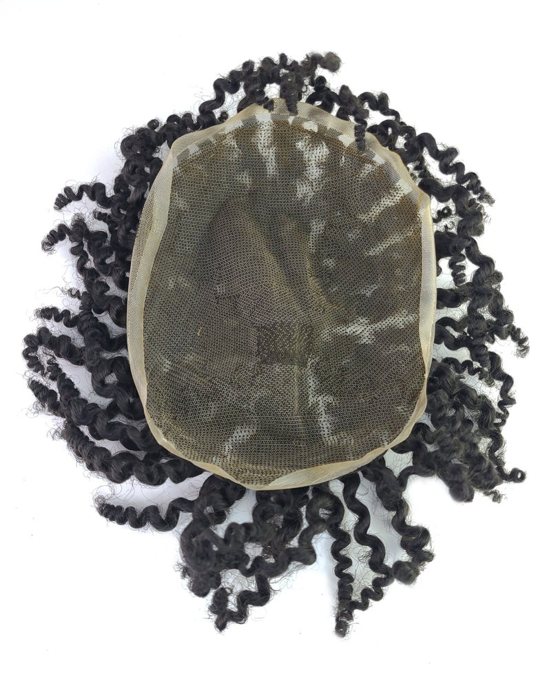 Pu&ograve; includere: Un'extension di capelli ricci marrone scuro con una base in pizzo. I capelli sono acconciati in riccioli stretti e mossi, che si irradiano verso l'esterno dal centro. La base in pizzo &egrave; di colore beige chiaro, progettata per fondersi con la pelle.