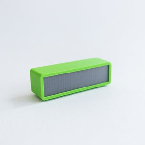 May include: A small, bright green rectangular device with a black display screen. The device is made of plastic and has a smooth, glossy finish.