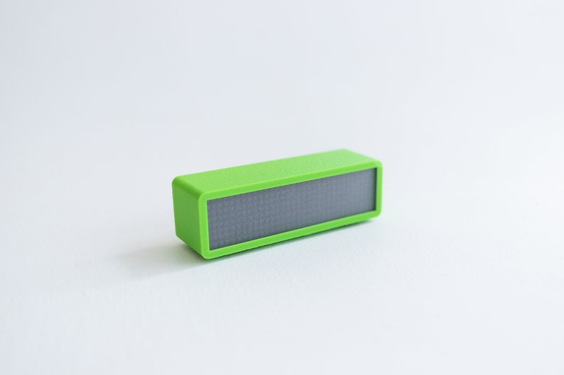 May include: A small, bright green rectangular device with a black display screen. The device is made of plastic and has a smooth, glossy finish.