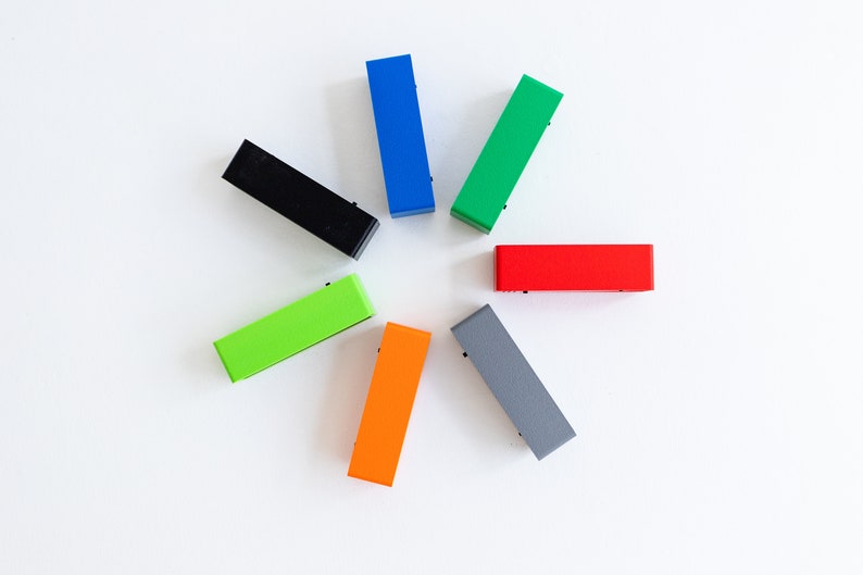 Puede incluir: Siete bloques rectangulares de diferentes colores dispuestos en un c&iacute;rculo. Los colores son negro, azul, verde, rojo, naranja, gris y verde lima.