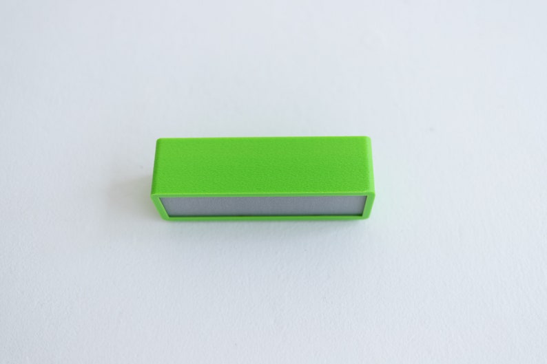 May include: A small, rectangular, green speaker with a gray front panel.