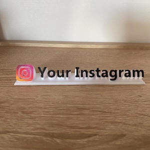 May include: White plastic sign with the Instagram logo and the text "Your Instagram" in black.