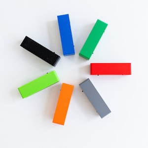 May include: Seven rectangular blocks in different colors arranged in a circle. The colors are black, blue, green, red, orange, gray, and lime green.
