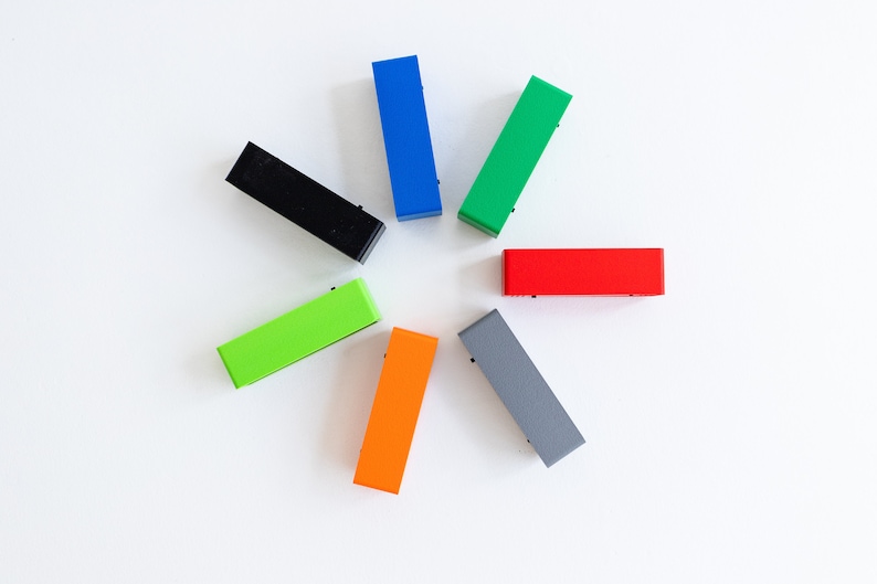 May include: Seven rectangular blocks in different colors arranged in a circle. The colors are black, blue, green, red, orange, gray, and lime green.