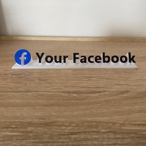 Pode incluir: Uma placa branca com um logotipo do Facebook azul e o texto "Your Facebook" em preto.