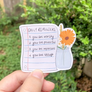 May include: A white sticker with a handwritten list of daily reminders: "you are worthy", "you are powerful", "you are important", and "you are enough". A drawing of a jar with flowers is next to the list.