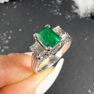 Anillo vintage de platino de los años 40 con tres piedras de esmeralda y diamantes en una banda decorativa