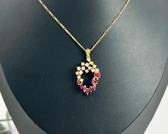 May include: A gold chain necklace with a pendant featuring a circle of pink and white stones.