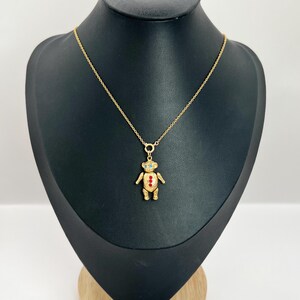 Op de afbeelding: Een gouden ketting met een teddybeer hanger. De beer heeft rode en blauwe emaille accenten.