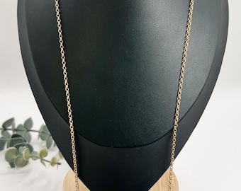 May include: A gold chain necklace on a black display stand. The chain is a simple, delicate design.