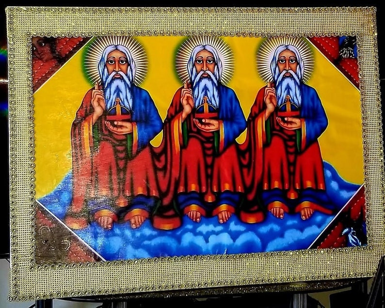 May include: A framed painting depicting three figures with white beards and halos, wearing red and blue robes, seated on a cloud. The background is yellow with a gold frame.