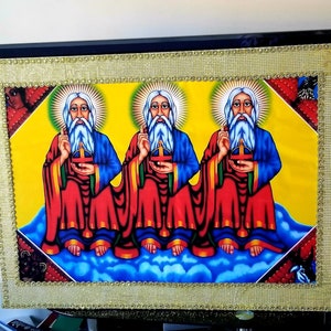 May include: A framed religious artwork featuring three figures with long white beards and halos, wearing red and blue robes, seated on clouds against a yellow background.