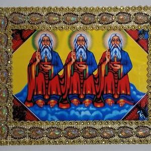 May include: A framed religious icon with three figures in red and blue robes, sitting on a cloud with a yellow background. The frame is gold with a decorative border.