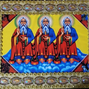 May include: A framed religious icon depicting three figures with white beards and halos, wearing red and blue robes, holding a cross and sitting on clouds against a yellow background.