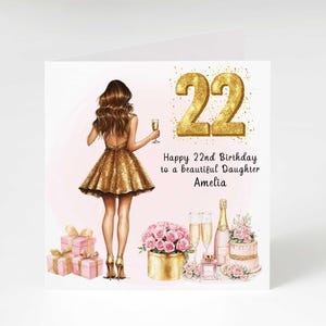 May include: A birthday card with a gold glitter design. The card features a drawing of a woman in a gold dress, holding a champagne glass. The text reads "Happy 22nd Birthday to a beautiful Daughter Amelia."