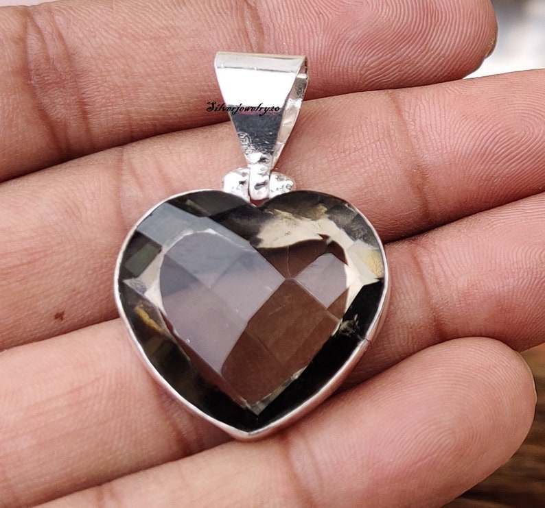 Pode incluir: Um pingente de prata em forma de cora&ccedil;&atilde;o com uma gema de quartzo fumado transparente. O pingente tem uma argola para prender a uma corrente.