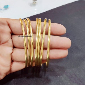 May include: A set of seven gold-colored bangles. The bangles are stacked on top of each other and are all the same size and width.