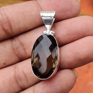 K&ouml;nnte beinhalten: Ein silberner Anh&auml;nger mit einem gro&szlig;en, facettierten, ovalen Rauchquarz-Edelstein. Der Anh&auml;nger ist mit "Silverjewelry20" gekennzeichnet.