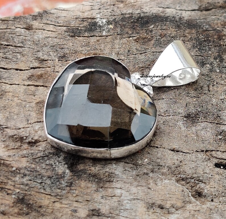 Pode incluir: Um pingente de prata em forma de cora&ccedil;&atilde;o com uma pedra preciosa de quartzo fumado escuro. O pingente tem uma argola para prender a uma corrente.