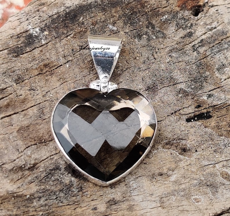 Pode incluir: Um pingente de prata em forma de cora&ccedil;&atilde;o com uma pedra preciosa de quartzo fumado escuro. O pingente mede aproximadamente 2,5 cm de di&acirc;metro.