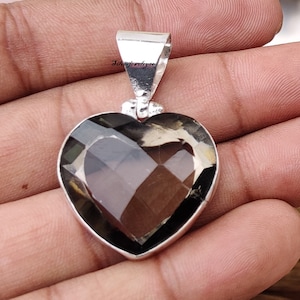 Pode incluir: Um pingente de prata em forma de cora&ccedil;&atilde;o com uma pedra preciosa de quartzo fumado. O pingente tem um aro para prender a uma corrente.