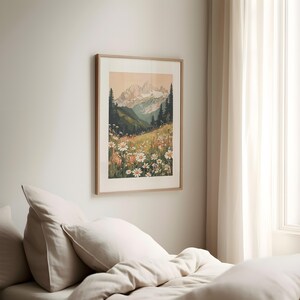 May include: A framed print of a mountain landscape with a field of white daisies in the foreground. The mountains are in the background and are a light brown color. The sky is a light blue color.