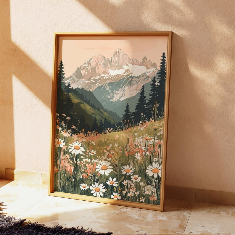 May include: A framed print of a mountain landscape with a field of white daisies in the foreground. The mountains are snow-capped and the sky is a soft pink.