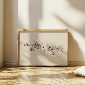 以下が含まれることがあります： 枕の上で眠る犬の白黒の絵。犬は丸まって、頭を足の上に置いています。絵は明るい木製の額縁に入っています。