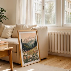 May include: A framed print of a mountain landscape with a field of white flowers in the foreground. The mountains are a soft pink and orange color, and the sky is a light blue. The print is in a wooden frame.