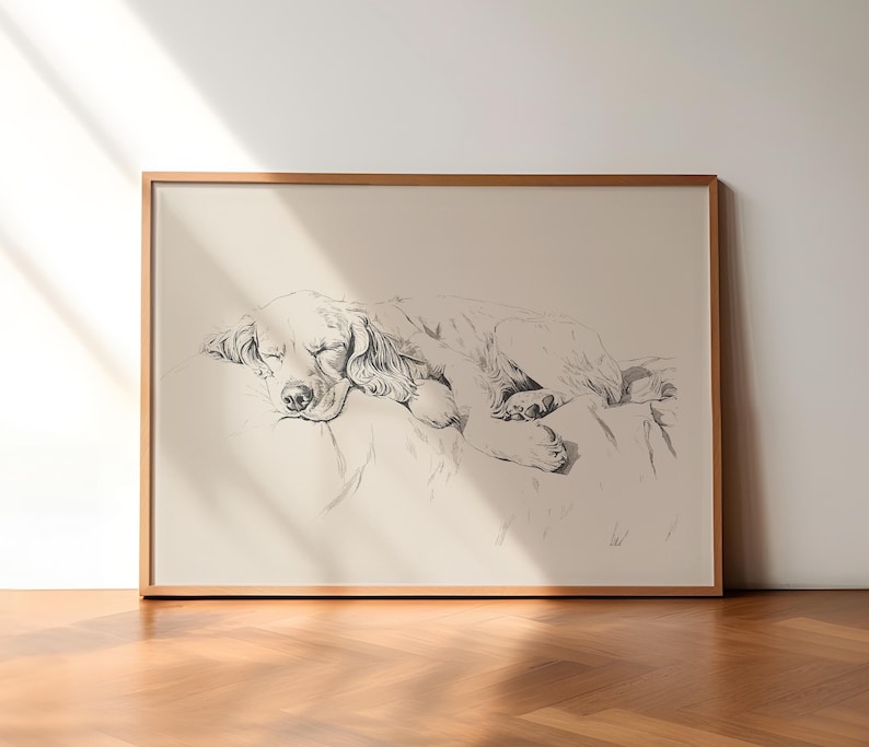 以下が含まれることがあります： 枕の上で眠る犬の白黒の線画。犬は丸まって、頭を足の上に置いています。絵は明るい木製の額縁に入っています。