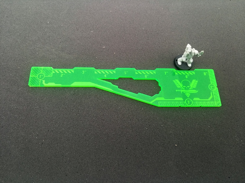 May include: A green plastic ruler with markings for 1 to 7 inches. The ruler is shaped like a spaceship with a skull and crossbones logo.