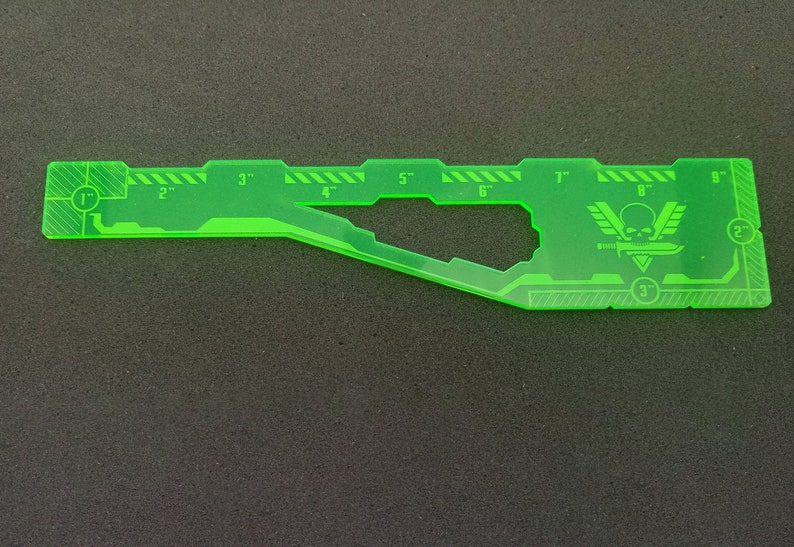 May include: A green plastic ruler with markings for 1 to 9 inches. The ruler has a skull and crossbones logo with the text "V" on either side of the skull.