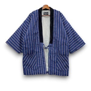May include: A blue hanten jacket featuring vertical stripes in shades of blue, white, and orange. The garment has a black velvet collar, a light-colored interior lining, two front pockets, and a small tie closure. A label reads "はんてん".