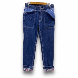 Op de afbeelding: Blauwe denim jeans met een geruite zoom en een blauwe en witte stippenvoering op de zakken.