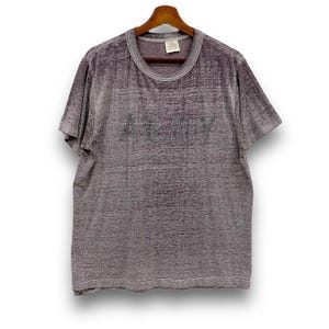 May include: A heathered gray t-shirt with the word "ARMY" printed across the chest. The short-sleeved shirt is hanging on a wooden hanger against a white background. The fabric has a textured appearance.