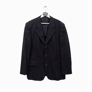 Op de afbeelding: Een donkerblauwe pinstripe blazer met een drieknoopsluiting.