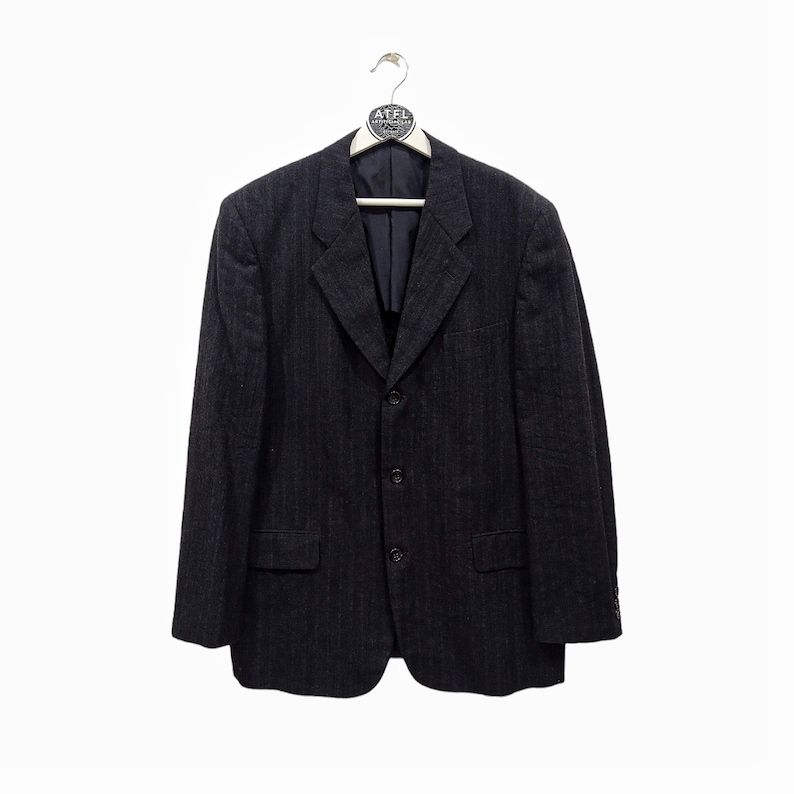 Op de afbeelding: Een donkerblauwe pinstripe blazer met een drieknoopsluiting.
