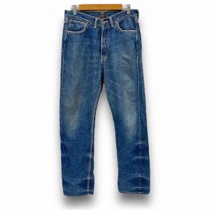 May include: A pair of blue denim jeans with a straight leg fit. The jeans have a button fly and five pockets.