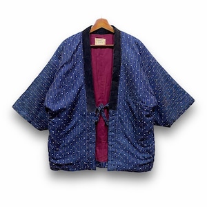 Könnte beinhalten: Blaue japanische Kimono-Jacke mit gepunktetem Muster und vertikalen Streifen. Die Jacke hat einen schwarzen Samtkragen und ein bordeauxfarbenes Innenfutter. Sie hängt an einem Holzbügel.