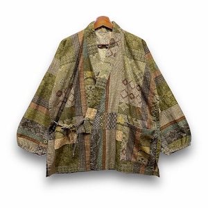 Könnte beinhalten: Kimono-Jacke im Patchwork-Stil in Grün-, Braun- und Beigetönen. Die Jacke hat einen V-Ausschnitt, lange Ärmel und zwei Vordertaschen mit Kordelverschlüssen. Der Stoff ist mit verschiedenen geometrischen und floralen Mustern versehen.
