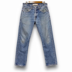 May include: Light blue denim jeans with a regular fit, displayed on a wooden hanger. The jeans show signs of wear with faded areas and slight distressing. The jeans have a classic five-pocket design and a button and zip closure.