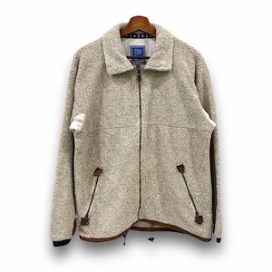 May include: A beige fleece jacket with a zipper closure and a brown leather trim. The jacket has a small blue patch with the word "air" on it.