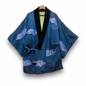 Könnte beinhalten: Ein dunkelblaues Kimono-Kleid mit einem schwarzen Samtkragen und einem hellgrünen Futter. Das Kleid hat ein gestepptes Design mit hellblauen und lila Blumenmustern. Es wird auf einem Holzbügel präsentiert.