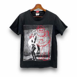 May include: Black t-shirt featuring a black and white image of Marilyn Monroe with a red outline of a person embracing her. The words "I love you" are written in red above the figures.