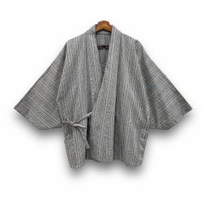 May include: A gray and white striped kimono-style robe with wide sleeves, hanging on a wooden hanger. The robe has a tie closure at the waist and a pocket on the front. The fabric appears to be a woven material.