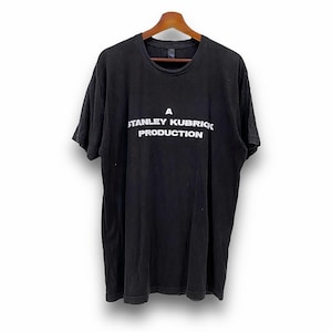 Könnte beinhalten: Ein schwarzes T-Shirt mit einem weißen Aufdruck, der "A Stanley Kubrick Production" lautet.